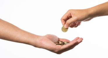 Woman Hand Giving Golden Coin To Another Hand.